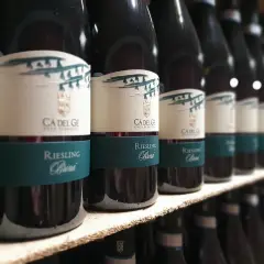 Bottiglie di vini oltrepò pavese, Riesling Brina, in fila su uno scaffale.