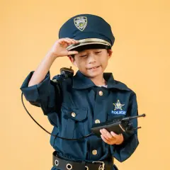 Dziecko w stroju policjantki, z czapką i krótkofalówką, gotowe do akcji.