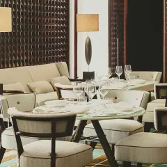 Eleganza in un ristorante di Milano: tavoli apparecchiati, divani accoglienti e luci soffuse creano un'atmosfera raffinata.
