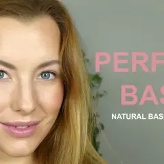 En kvinna med blå ögon och blont hår ler. Hon har precis applicerat foundation för en perfekt bas.