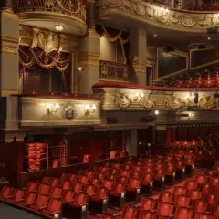 Luksusowe wnętrze teatru z czerwonymi fotelami i złotymi zdobieniami. Zastanawiasz się, ile trwa przedstawienie w teatrze?