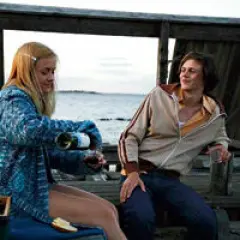 Två unga personer på en brygga, en häller upp vin. En scen som kunde vara från svenska filmer 2010-talet.