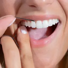 Dita curate usano filo interdentale abrasivo per pulire i denti bianchi e brillanti.