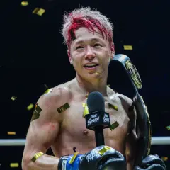 Fighter with red-streaked hair holds a championship belt, confetti falling. This victory might be the tko retirement meaning for his career.