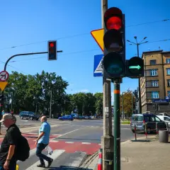 Sygnalizator S2 z zieloną strzałką w prawo, czerwonym światłem u góry. Ludzie przechodzą przez pasy.