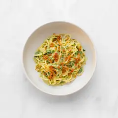 Spaghetti alla carrettiera mit frischer Petersilie, Chili und knusprigen Semmelbröseln in einer weißen Schüssel auf Marmor.