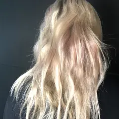En person med blont, vågigt hår med inslag av rosa nyanser. En ny hårfärg som ger en unik look.