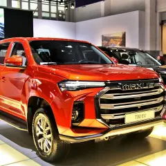 Pomarańczowy Maxus T90 EV, chińska marka samochodów w Polsce, prezentuje się na wystawie.