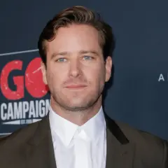 Armie Hammer, med sina blå ögon och mörk kostym, poserar framför en bakgrund med texten "GO CAMPAIGN".
