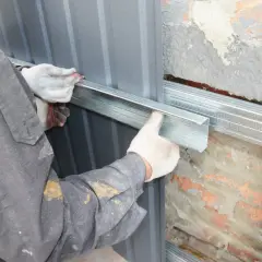 Arbeiter montiert Metallprofile für die Abdichtung des Hauses.