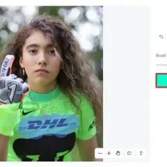 Jeune gardienne de but avec un gant, prête à enlever logo sur son maillot vert fluo.