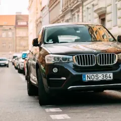 Czarny SUV zaparkowany na ulicy, przypominający o przepisach dotyczących zastawiania bramy wjazdowej.