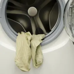 Para skarpetek wisi na drzwiach pralki. Mimo czyszczenia, pralka śmierdzi, a skarpetki wyglądają na zużyte.