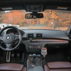 Wnętrze BMW z brązową tapicerką, kierownicą i panelem. Na desce rozdzielczej kubek kawy. Idealne miejsce na podpisanie umowy sprzedaży samochodu.
