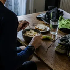 Préparation pour un semi-marathon : un bol de flocons d'avoine aux bananes, une tranche de pain, une banane, une verre d'eau, des chaussures de course et des vêtements.