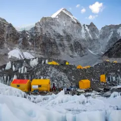 Obóz u podnóża Mount Everest, gdzie **mount everest wysokość** jest wyzwaniem. Żółte namioty na lodowcu, w tle majestatyczne, skaliste szczyty.