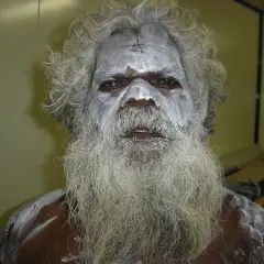 En aboriginal model med vitt ansiktsmåleri och långt grått skägg.