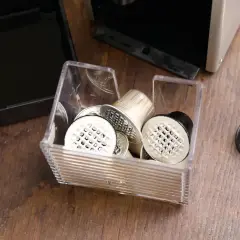 Pojemnik z kapsułkami do Nespresso, obok ekspresu i tacki na zużyte kapsułki. Czas na odkamienianie!