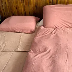 A bedspread can be used as a blanket, as shown by this cozy, pink-covered bed with a wooden headboard.