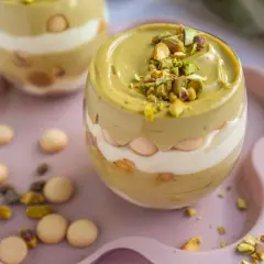 Pyszny deser w pucharku: krem pistacjowy z mascarpone, przełożony biszkoptami i posypany pistacjami.