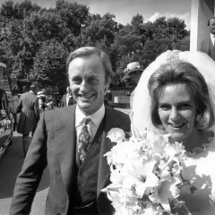 Młoda Camilla Parker Bowles w dniu ślubu, uśmiechnięta z bukietem kwiatów, obok pana młodego.