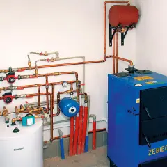 Instalacja grzewcza z kotłem, zasobnikiem i pompami obiegowymi. System zapewnia ogrzewanie podłogowe i grzejniki na jednym obiegu.