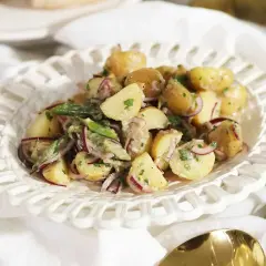 En krämig potatissallad med rödlök och örter, ser ut att vara den godaste potatissalladen för en sommarbuffé.