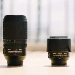 A long telephoto lens stands next to a compact wide-angle lens, showcasing the difference between wide angle vs telephoto perspectives.