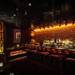 Interni di un bar londinese famosi, con mattoni a vista, illuminazione d'atmosfera e una vasta selezione di liquori dietro il bancone.