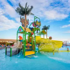 Kolorowy aquapark z palmami i zjeżdżalniami, idealne miejsce na wakacje w Eftalia. Dzieci bawią się w wodzie.