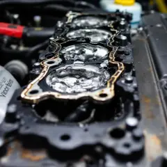 Joint de culasse endommagé, signe d'une fuite de liquide de refroidissement. L'intérieur du moteur est visible, avec des traces d'humidité.