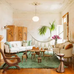 A serene boho space with a white sofa, macrame hammock, and eclectic decor.