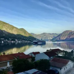 Widok na zatokę w Czarnogórze z górami w tle i statkiem wycieczkowym. Czy Czarnogóra jest bezpieczna? Tak, to spokojne miejsce na wakacje.