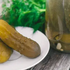 Dwa ogórki kiszone na talerzyku, obok słoik z ogórkami. Zastanawiasz się, dlaczego ogórki kiszone są puste w środku?