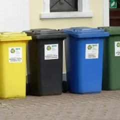 Cztery kolorowe kosze na śmieci: żółty (tworzywa sztuczne), czarny (metale), niebieski (papier) i zielony (szkło). Gdzie wyrzucić opakowanie po galaretce? Do żółtego kosza, jeśli jest plastikowe.