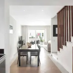 Comedor y sala de estar luminosos con escaleras de madera. Imagina cenar en el restaurante La Buganvilla San José.