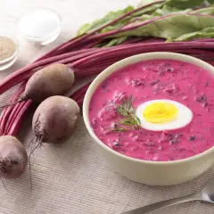 Chłodnik litewski, orzeźwiająca zupa z buraków, podana z jajkiem i koperkiem. Obok świeże buraki, sól i pieprz.