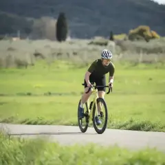 Kolarz w kasku i okularach wykonuje intensywny trening anaerobowy na rowerze, pochylony nad kierownicą.