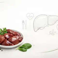 Surowa wątróbka na talerzu, obok czosnek i przyprawy. Grafika wątroby, serca i jabłka sugeruje, czy wątróbka jest zdrowa.