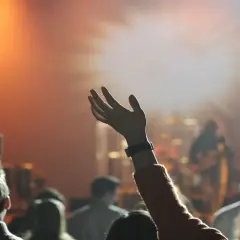 Menschen mit erhobenen Händen in einem Gottesdienst. Sie sind Teil der Pfingstbewegung, die sich durch lebendige Anbetung auszeichnet.