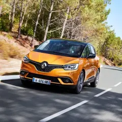 Pomarańczowy Renault Scenic 4 na krętej drodze. Choć wygląda świetnie, warto znać jego potencjalne wady przed zakupem.