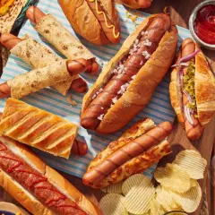 Un festin de hot-dogs pour un barbecue : pains variés, garnitures et chips.