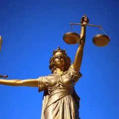Złota Temida z mieczem i wagą, symbol sprawiedliwości, przypomina o pozytywistycznym dążeniu do prawdy opartej na faktach.