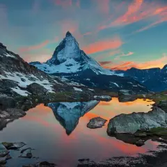 Zachód słońca nad jeziorem z odbiciem Matterhornu. Widok na wejście na Matterhorn, otoczone skalistymi zboczami i ośnieżonymi szczytami.