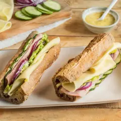 Deux sandwichs généreux, garni de jambon, fromage, concombre et oignon rouge. Le meilleur sandwich jambon fromage pour un déjeuner parfait.