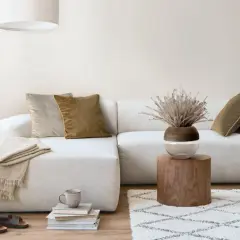 Przytulny salon boho z jasną sofą, drewnianymi meblami i naturalnymi dodatkami.