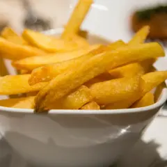 Chrupiące złote frytki w białej misce.