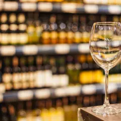 Verre à vin vide sur un comptoir, devant des étagères remplies de bouteilles. L'ambiance évoque une dégustation de vin à Paris.