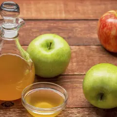 Apfelessig in einer Karaffe und Schale, daneben Äpfel. Vielseitige Apfelessig Anwendung für Küche und Gesundheit.