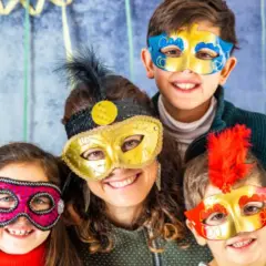 Familia sonriente con máscaras coloridas, celebrando lo que representa el carnaval.